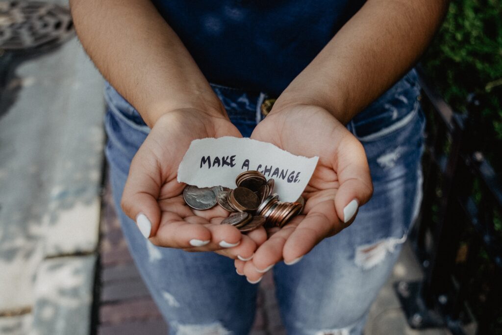 Open hands holding coins and a note that reads Make a Change
