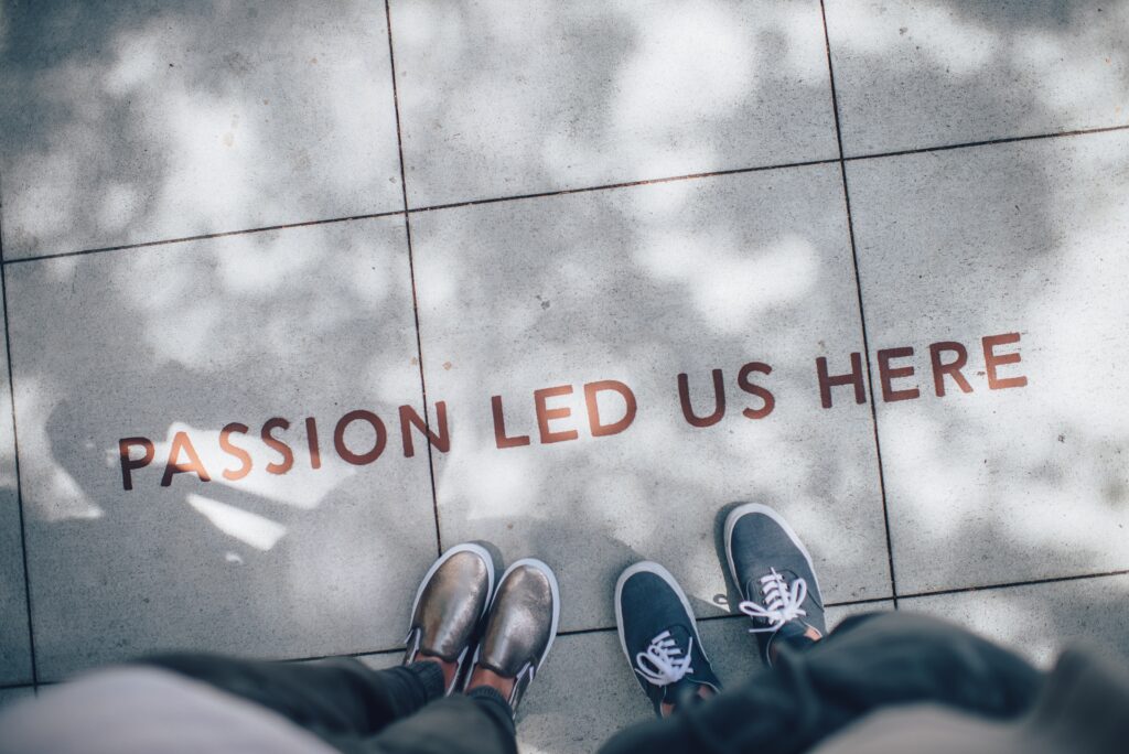 Sidewalk lettering that reads Passion Led Us Here, seen from above