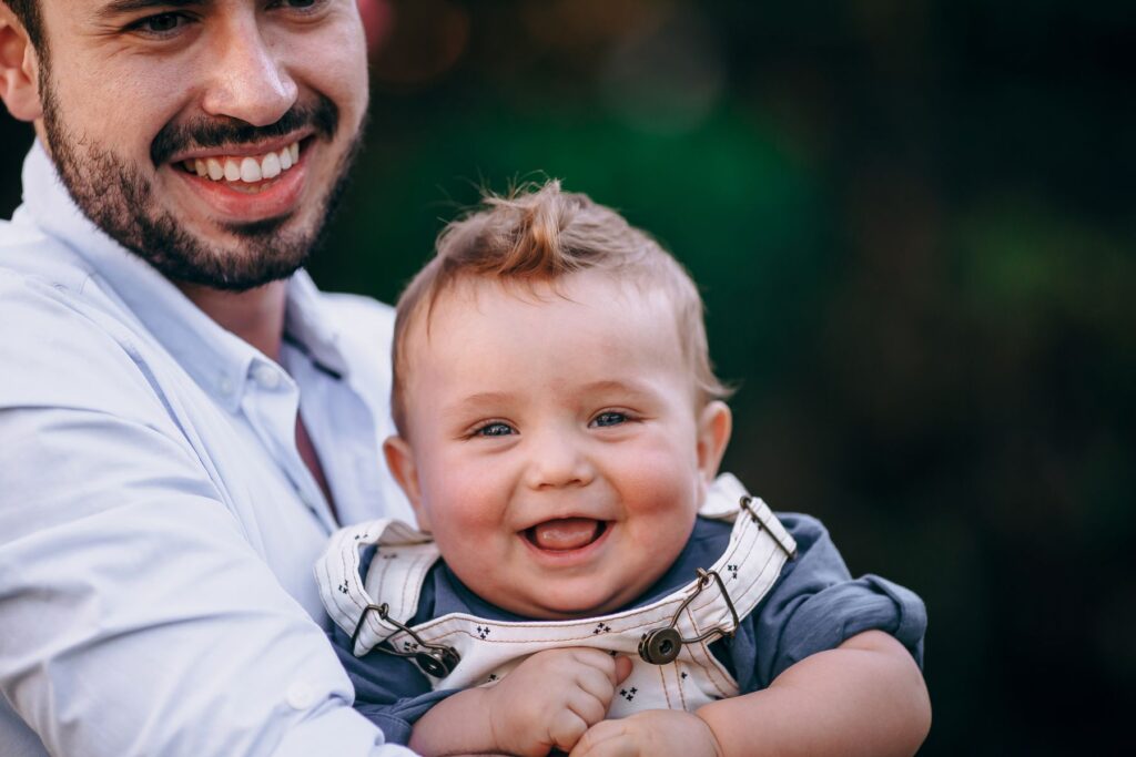A father holding his smiling baby outdoors in warm afternoon light